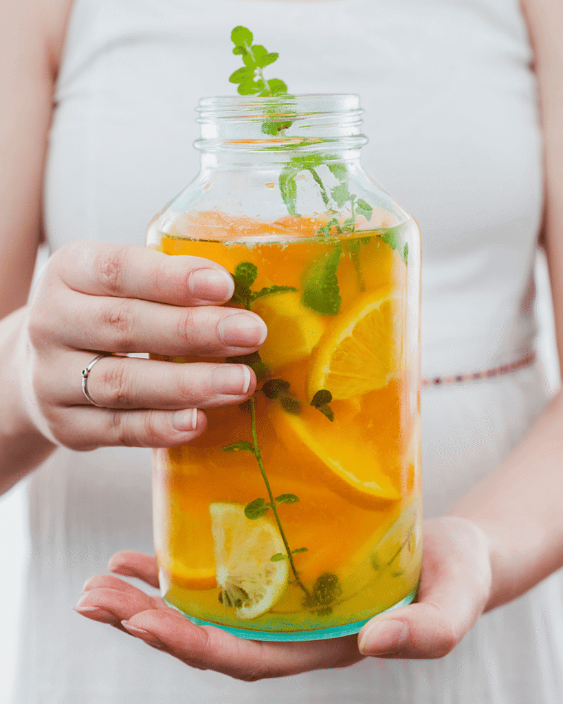 Upclose shot of woman holding a large jar of orange and lemon infused water