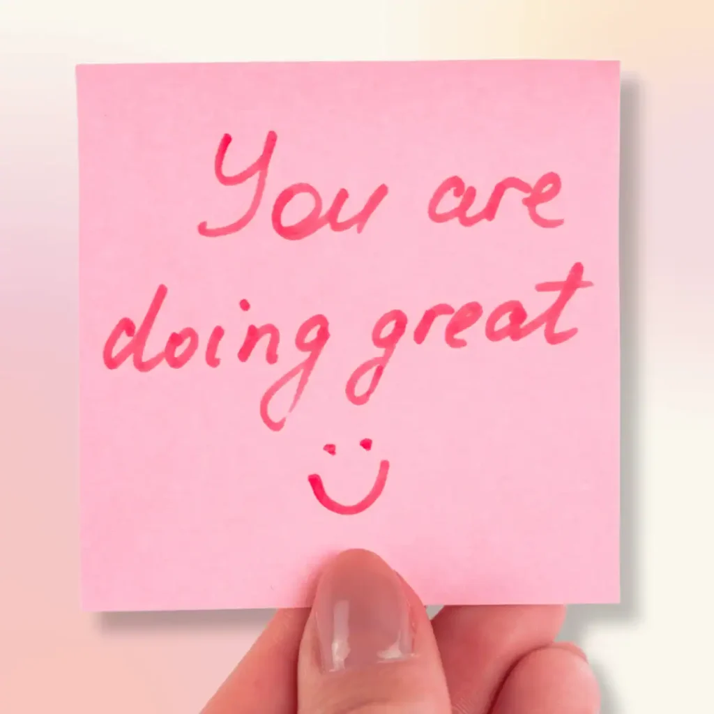 A-hand-holding-a-pink-post-it-note-that-says-You-are-doing-great
