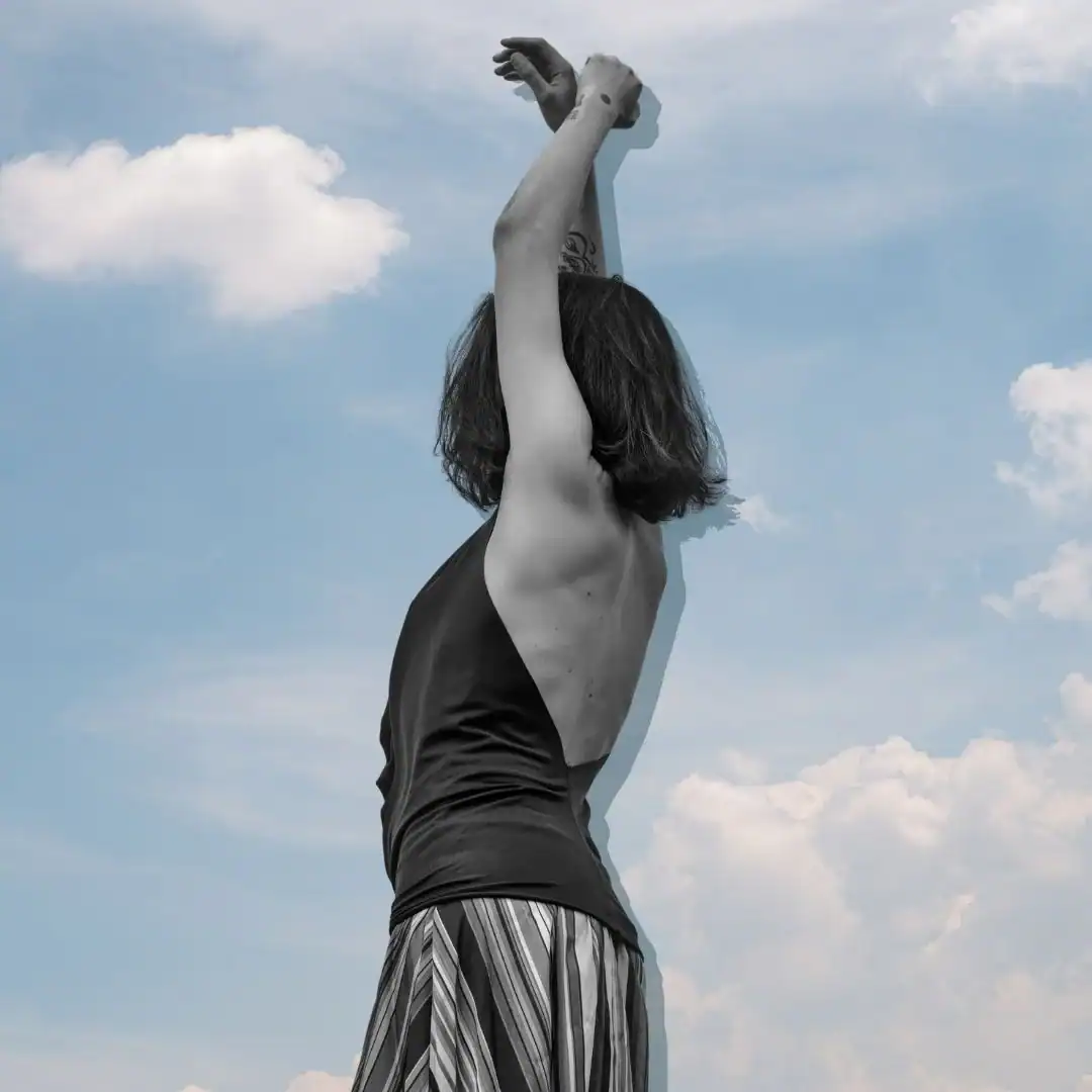 Anonymous-woman-raising-her-hands-against-cloudy-sky.-Self-Care-Sundays