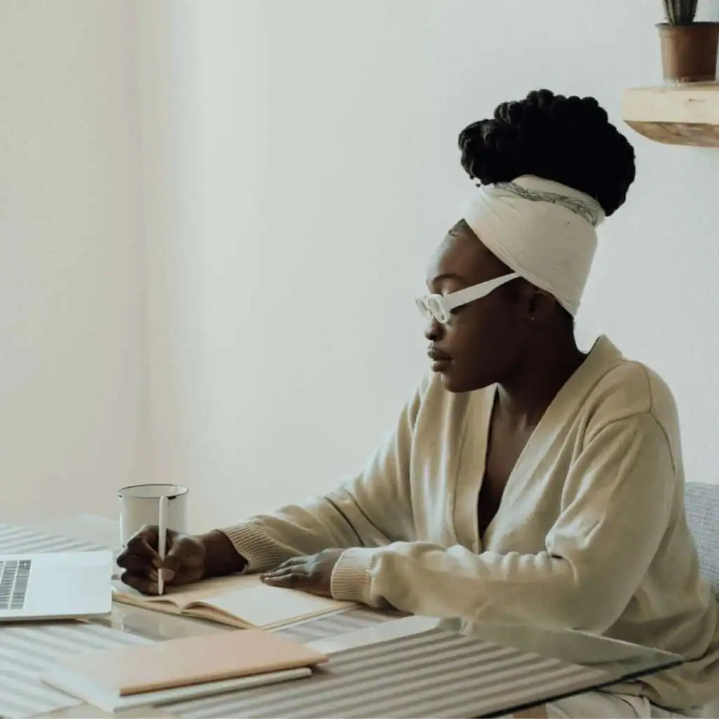 Black-woman-sitting-at-a-table-writing-in-a-notebook