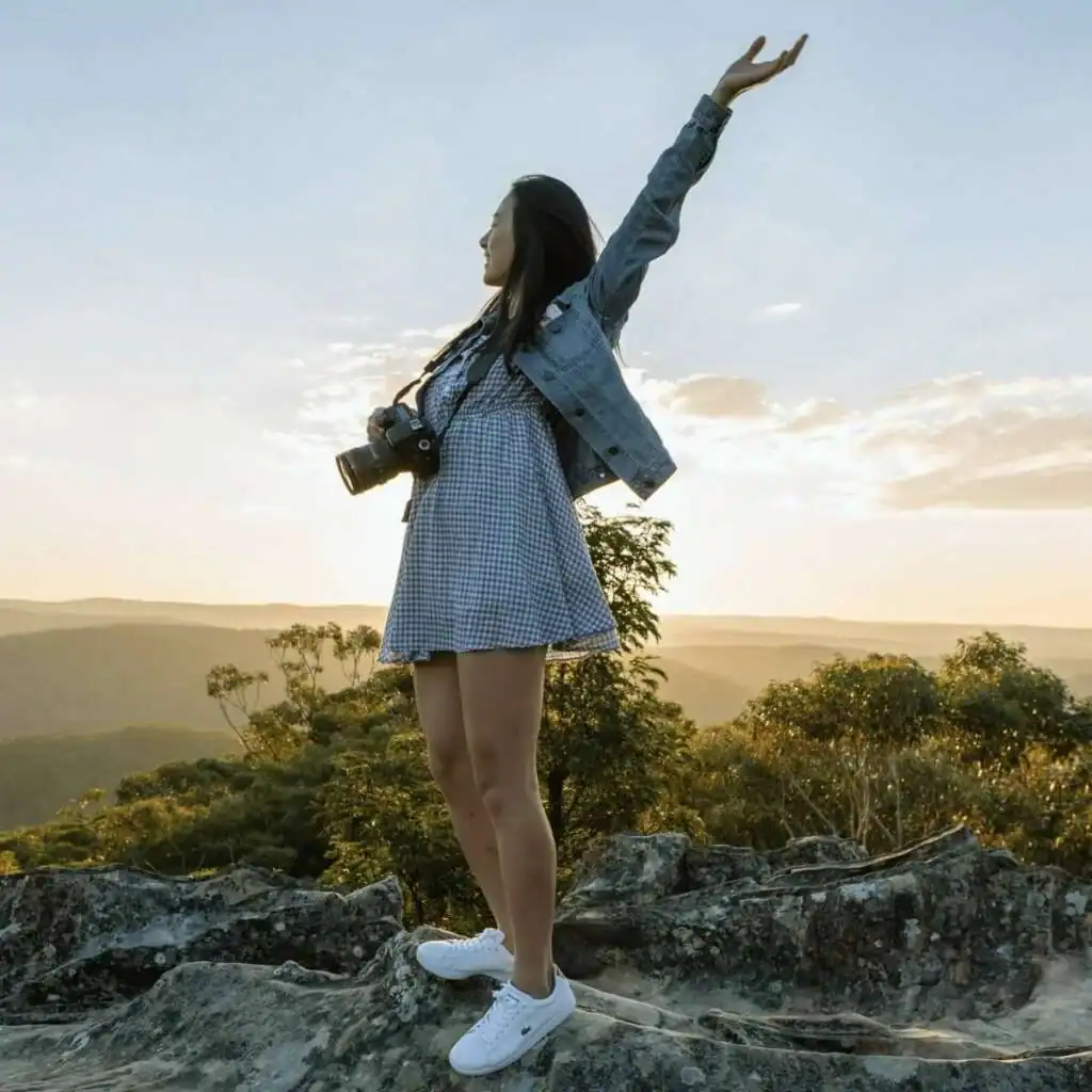 Medium-shot-of-woman-with-a-camera-around-her-neck-outside-on-a-mountain-top-surrounded-by-trees