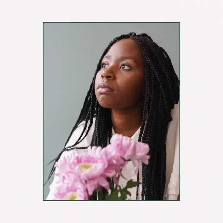 Pensive-young-African-American-lady-with-flower-bouquet-looking-away-dreamily