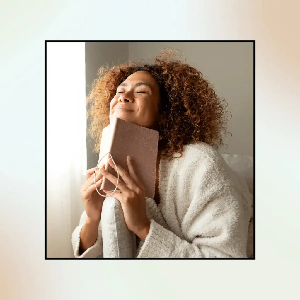 Smiling-Hispanic-Woman-with-Curly-Hair-Holding-Book-While-Sitting.-Scripting-Manifestation-Technique