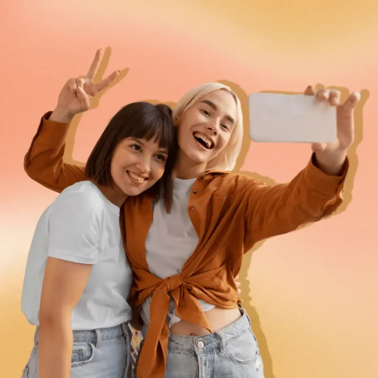 Two-friends-posing-for-selfie.-Background-is-an-orange-and-peach-gradient