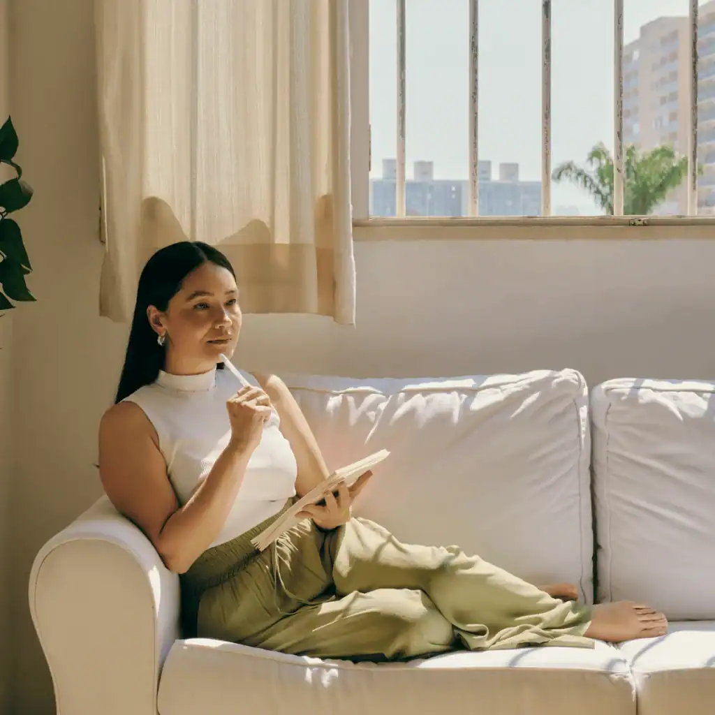 Woman-sits-on-her-cream-coloured-sofa-writing-in-her-journal