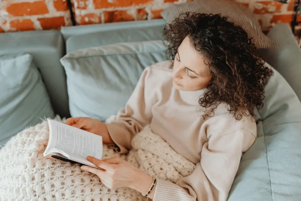A Woman Lying on Sofa while Reading a Book. Hygge Morning Routine Ideas
