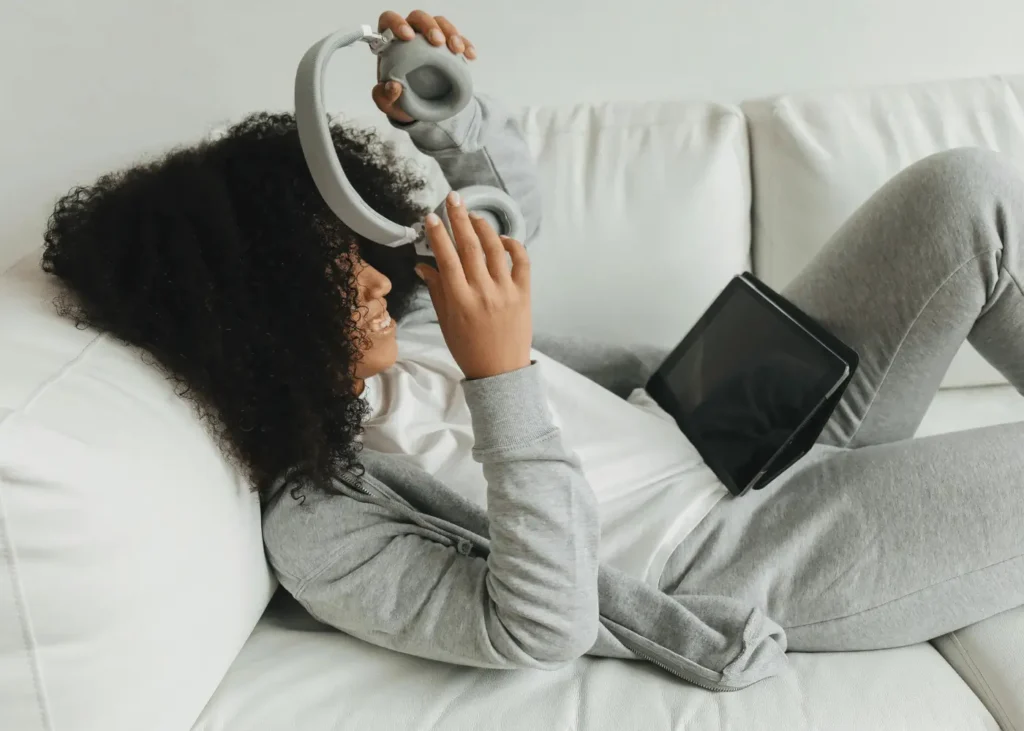 A Woman in Gray Sweater Lying Down Using a Headphones. Rainy day activities