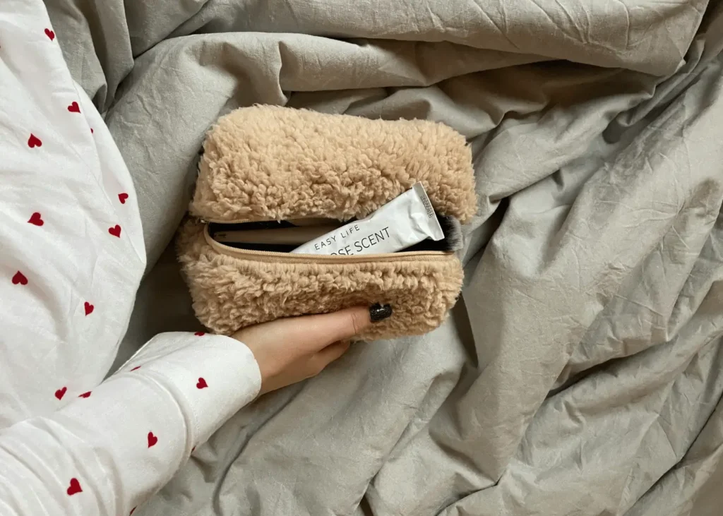 Woman Hand Holding Bag on Bedclothes