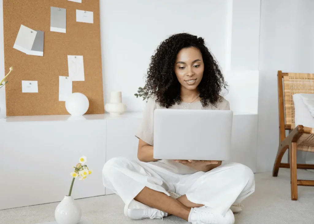 Woman in White Dress Shirt and White Pants Sitting on Floor Using Macbook. Positive Affirmations For Entrepreneurs