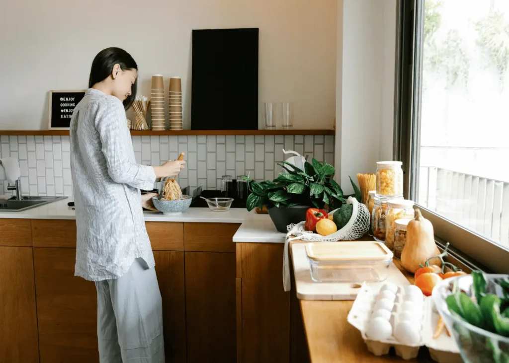 Young ethnic woman preparing ramen soup in kitchen