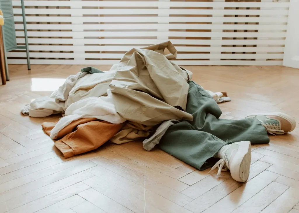 a woman lying down on the floor under a pile of clothes