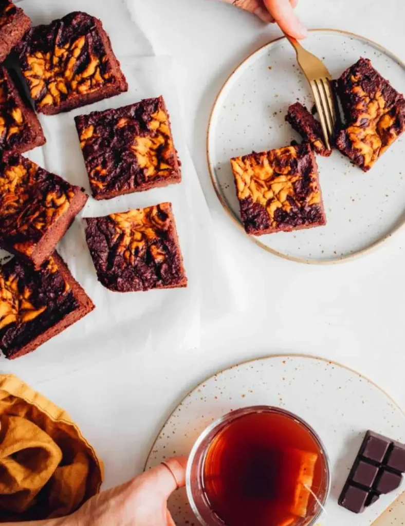 Vegan pumpkin brownies with an orange pumpkin swirl pattern on top, cut into squares