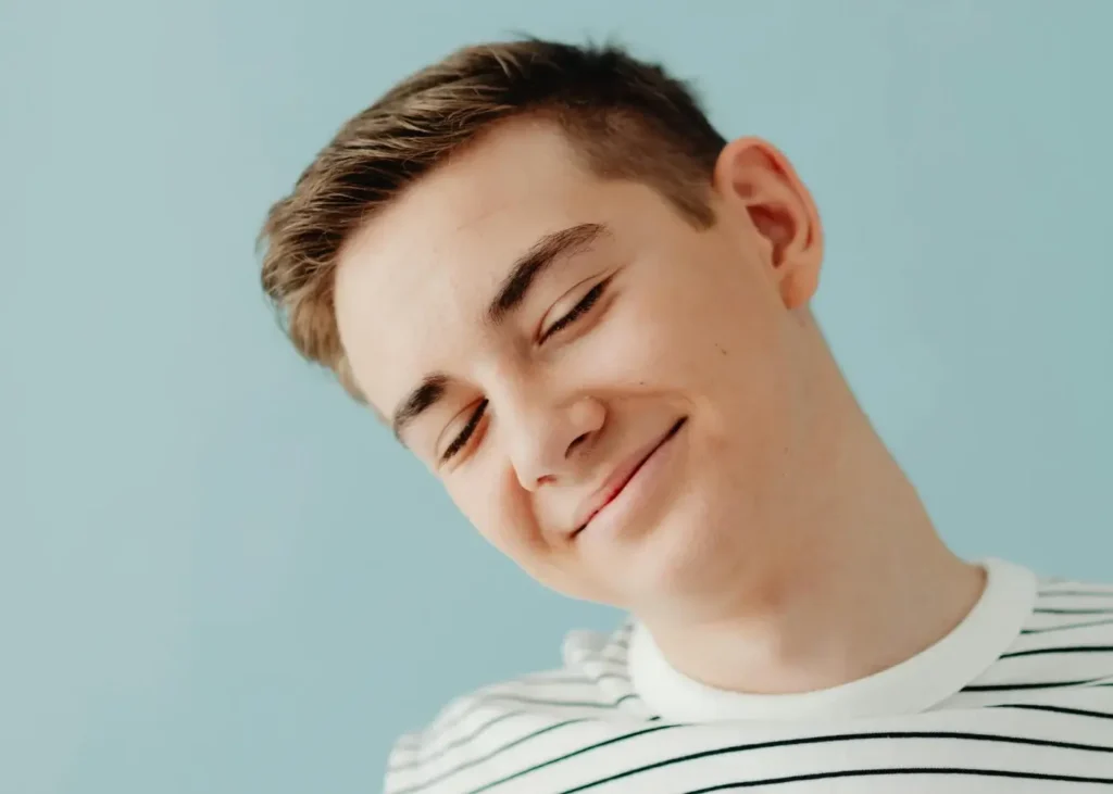 Teenage Boy in a Stripped Blouse Smiling with His Eyes Closed