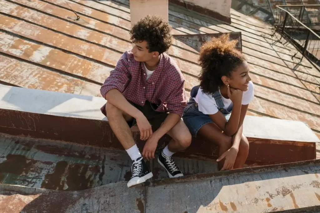 Teenage couple sitting on rooftop. Summer Bucket List Ideas For Teens