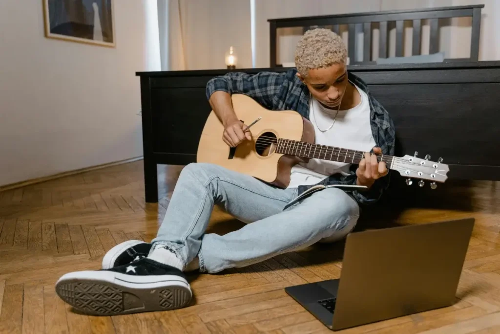 Young teen playing the guitar in his bedroom