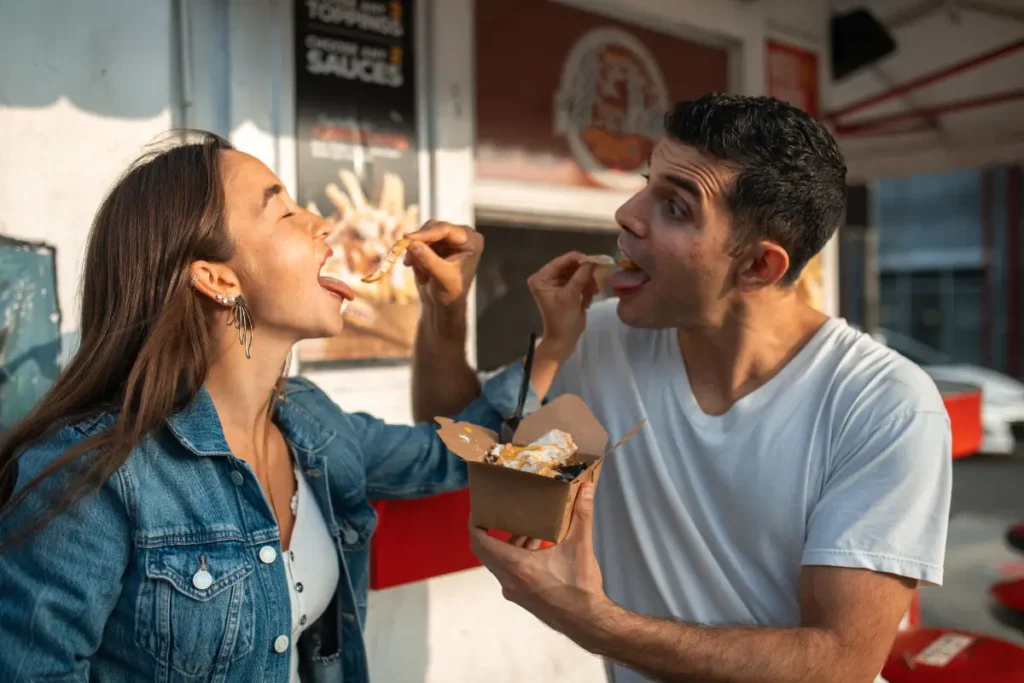 A couple having fun and sharing takeout food while enjoying a sunny day outdoors.. Couples Bucket List Ideas