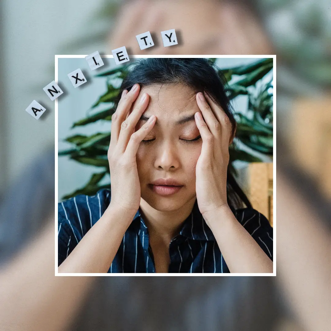 A woman sitting indoors, holding her head in stress or worry, surrounded by plants. Journal Prompts for Anxiety