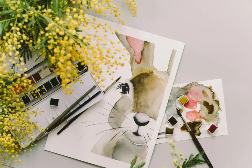 A watercolor painting of a bunny surrounded by mimosa flowers and art supplies. Hobbies for Women Over 40