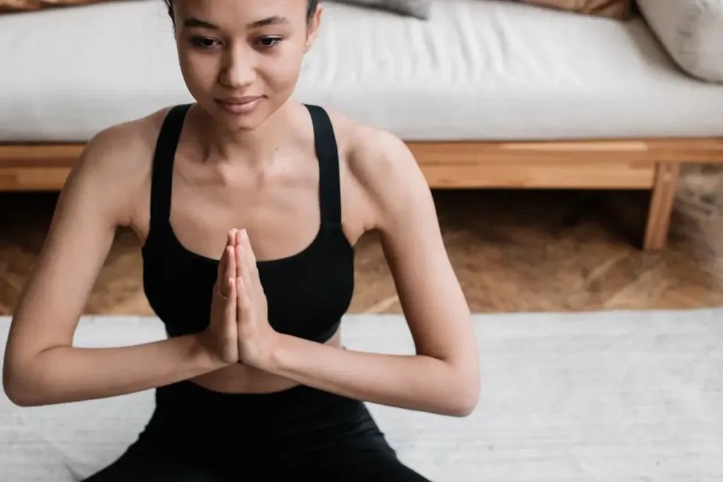 A woman in activewear meditating indoors, embodying peace and relaxation. Hobbies for Women Over 40