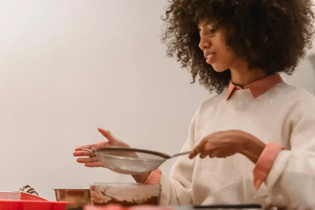 A young woman sifting ingredients while baking at home, focusing on her culinary process. Hobbies for Women Over 40