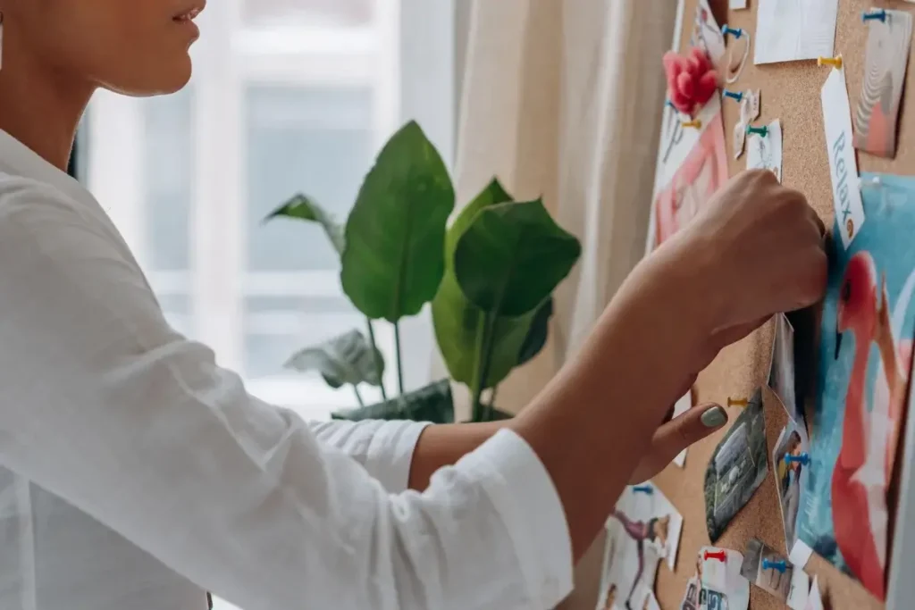 Close-up of a fashion designer arranging photos on an inspiration board indoors. Self-Care Bingo
