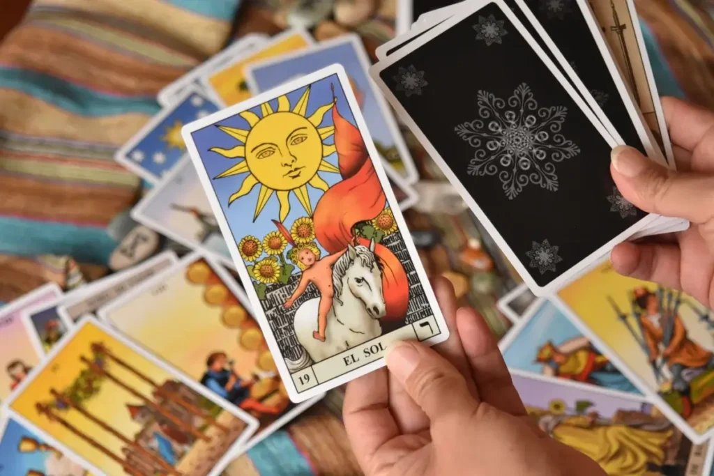 Close-up of tarot cards in hands, showcasing 'El Sol' card. Ideal for fortune-telling and spirituality themes. Hobbies for Women Over 40