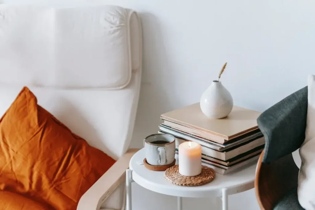 Inviting armchair setup with books, a lit candle, and a cup of tea, perfect for relaxation. Funny House Names