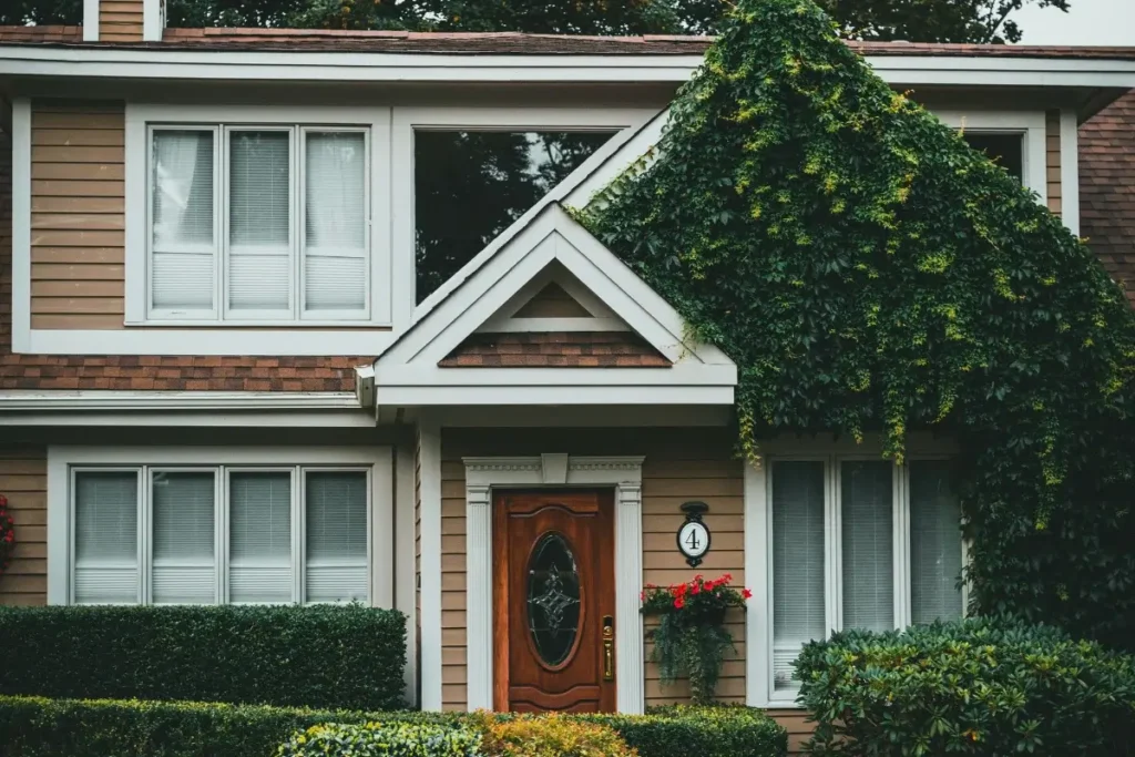 Picturesque suburban home featuring lush ivy and manicured shrubs, perfect for architectural themes. Funny House Names