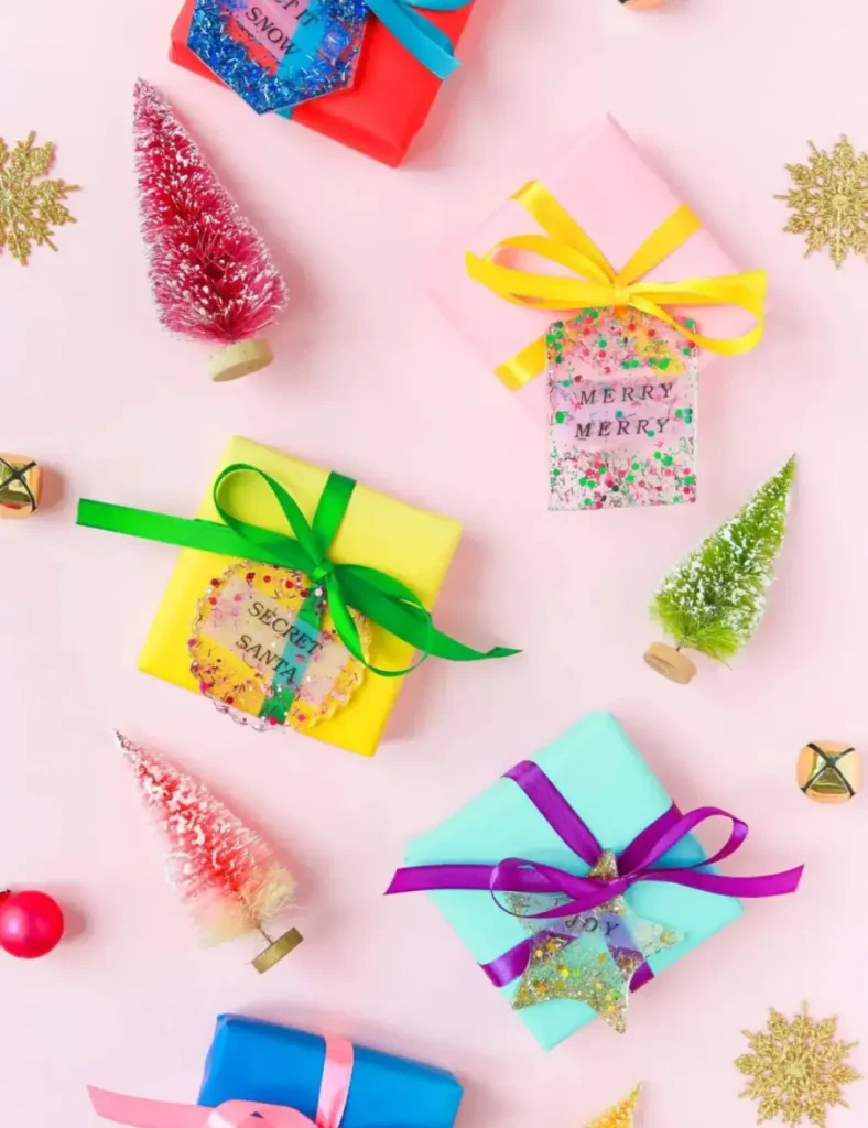 Glittery resin gift tags with printed ribbon text set inside, tied to wrapped presents.