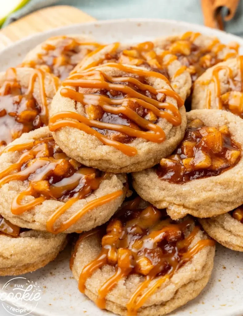 tack of sugar cookies topped with cinnamon apple pie filling and a caramel drizzle, on a speckled ceramic plate.