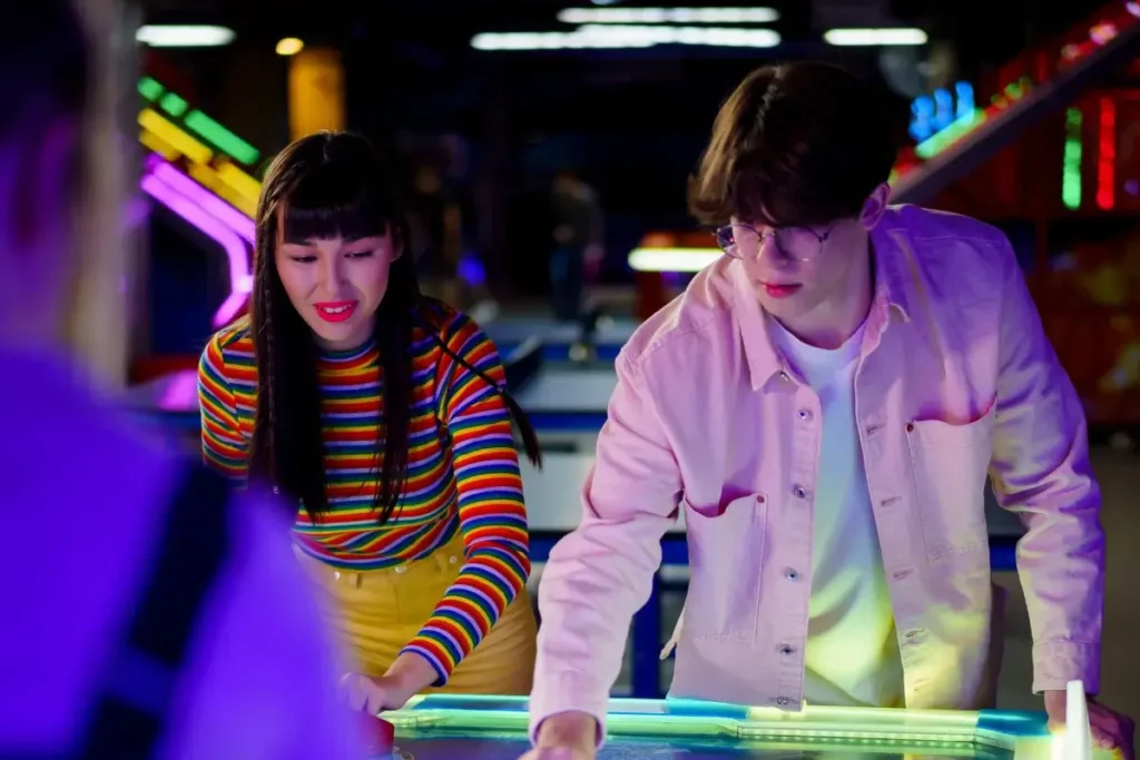 A young couple enjoys a fun air hockey match at an arcade, creating a lively atmosphere. Date Night Ideas