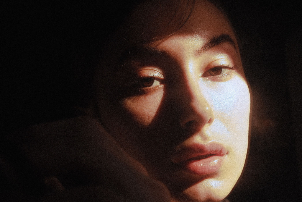 An artistic close-up portrait utilizing dramatic light and shadow for a moody effect.
