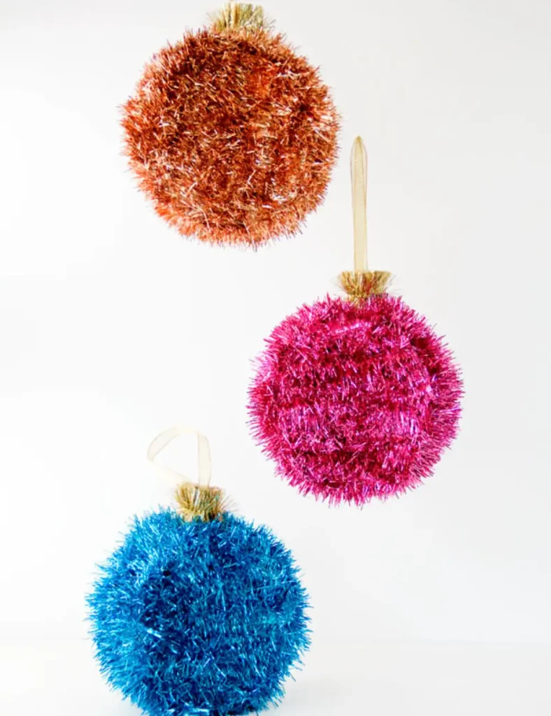 Bright tinsel-covered ornament piñatas with gold tops, hanging from ribbons.