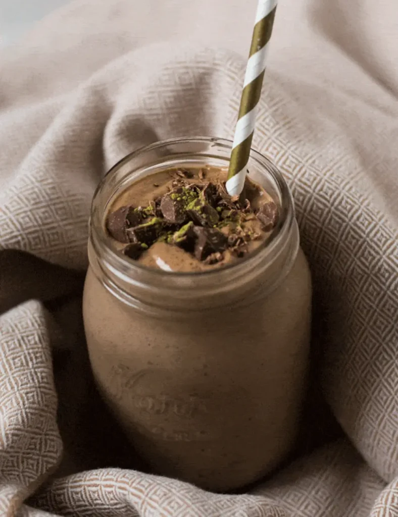 Chocolate matcha smoothie in a glass mason jar made with avocado, cacao, and peanut butter