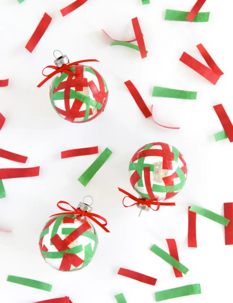 Christmas baubles covered in scattered strips of red and green tissue paper confetti.