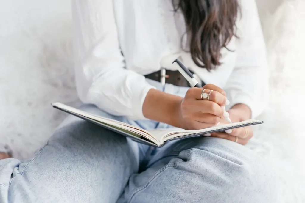 Close-up of a woman writing in a notebook, showcasing creativity and focus. Gratitude Journal Prompts
