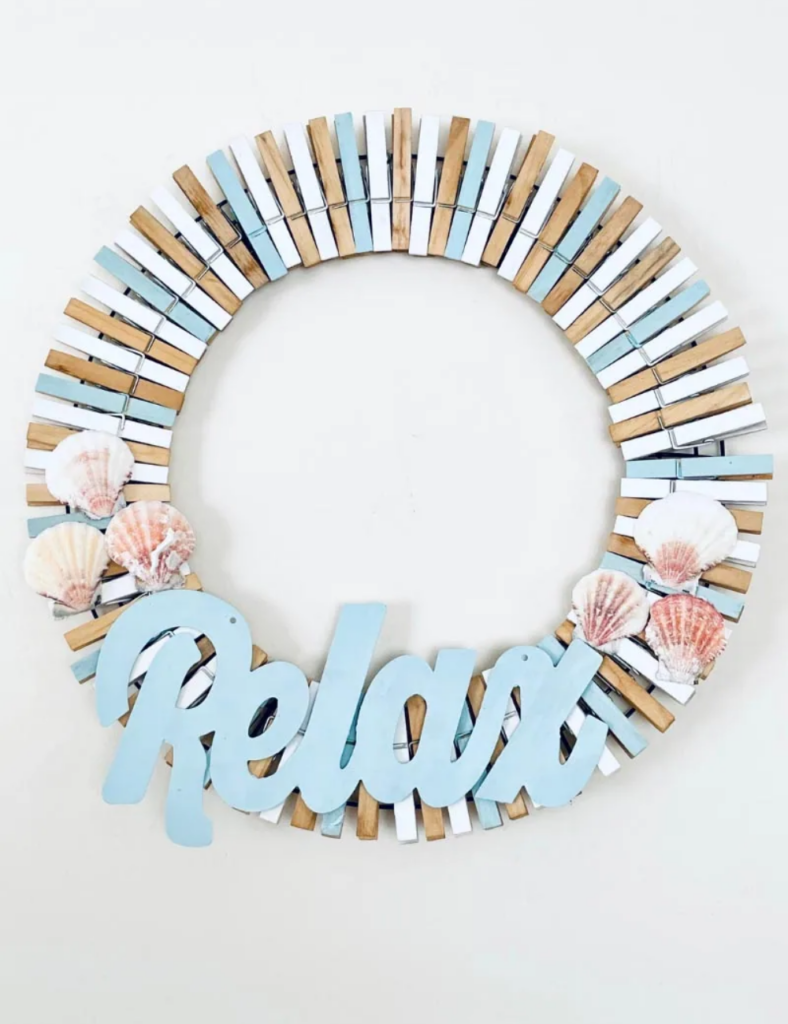 DIY coastal wreath made from white, blue and coffee-stained clothespins with scallop shells and a Relax sign