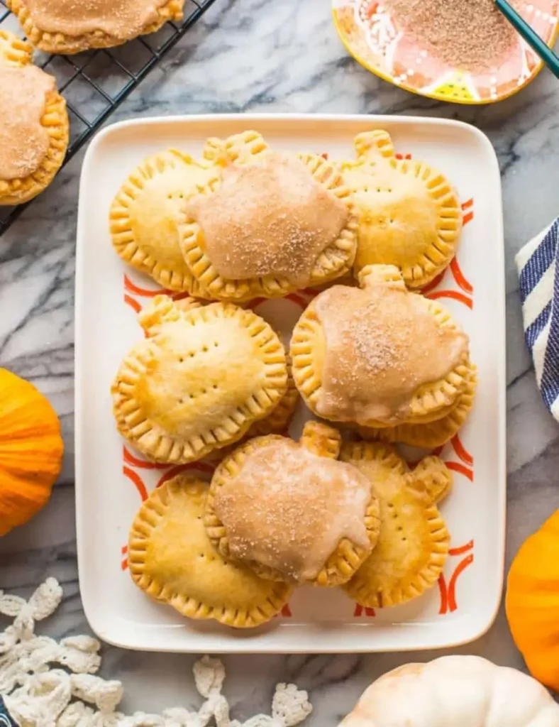 Gluten-free pumpkin pop tarts with white glaze and fall sprinkles on a decorative tray