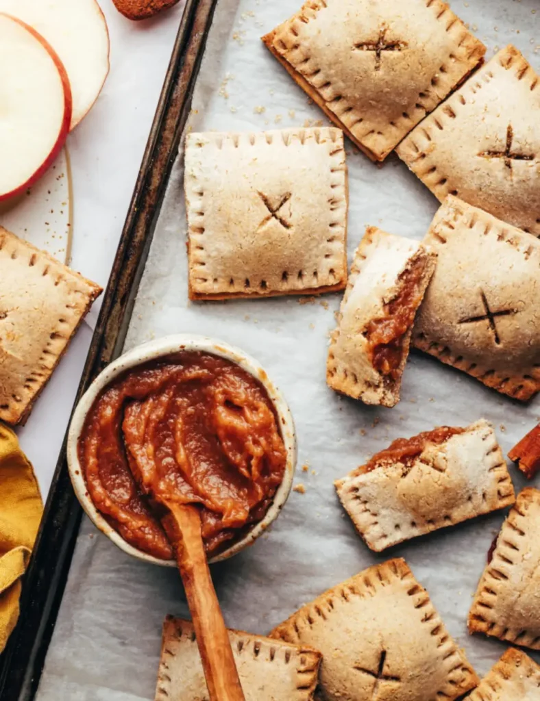 Gluten-free vegan apple butter pop tarts with icing on parchment paper
