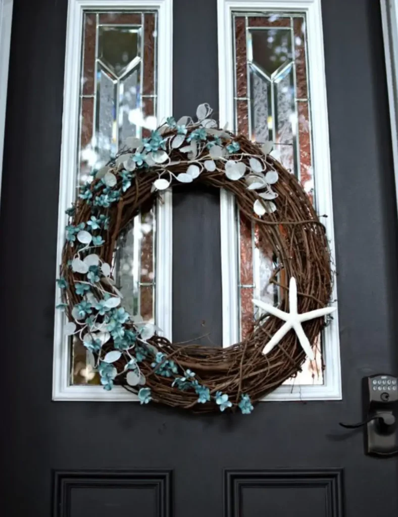 Grapevine wreath with blue and white faux flowers woven along one side and a starfish tied at the bottom