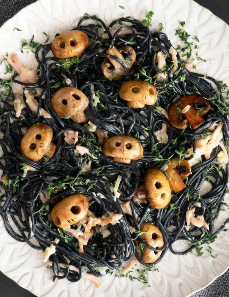 Black squid ink spaghetti in creamy bacon sauce topped with carved button mushroom skulls and fresh thyme