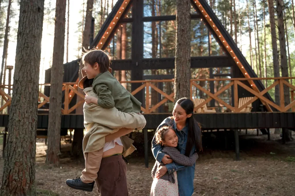 Happy family playing near a stylish A-frame cabin in a forest, enjoying outdoor time. airbnb name ideas