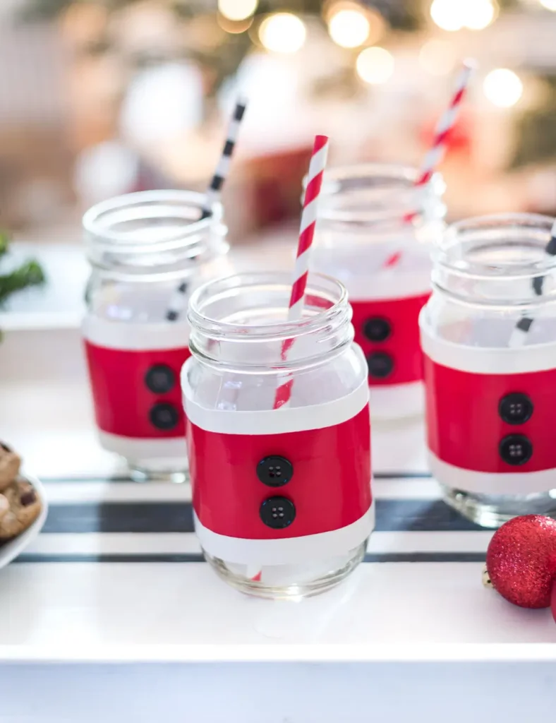 Mason jar wrapped in a red and white duck tape Santa suit cozy with two black buttons.