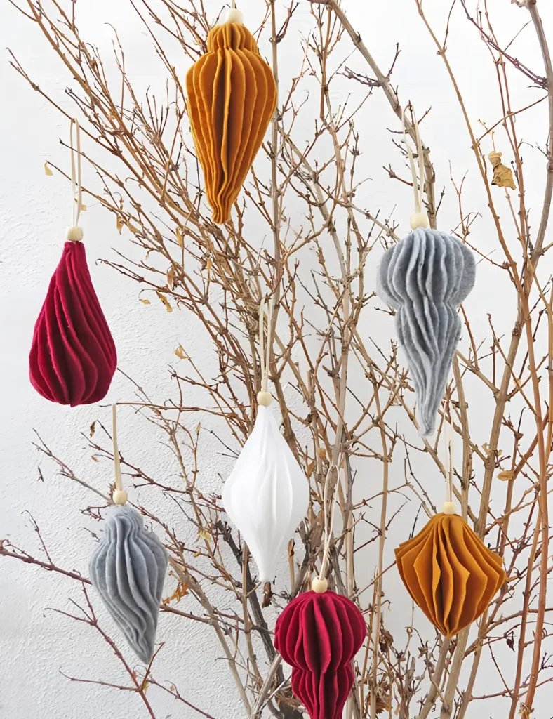 Modern layered felt Christmas ornaments in bell and tree shapes, stitched down the centre with ribbon loops.
