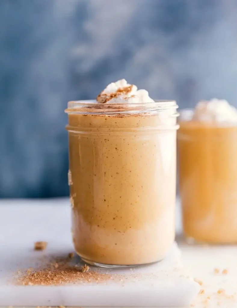 Pumpkin pie protein shake in a tall glass topped with cinnamon and whipped cream