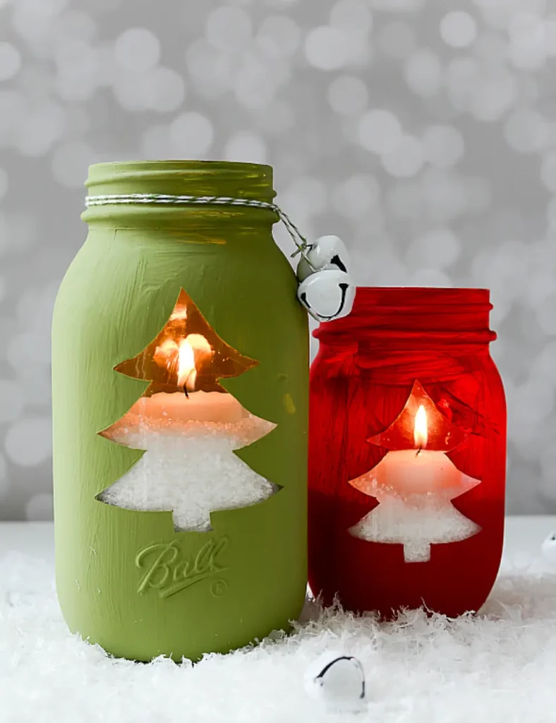 Red and green painted mason jars with a clear glass Christmas tree cutout, glowing from a tea light sitting on Epsom salt inside.