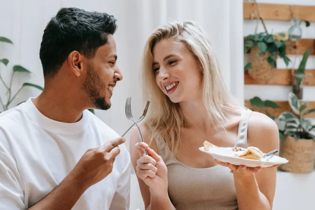 Smiling couple enjoying a meal indoors, exuding warmth and affection. Fun Date Night at Home Ideas