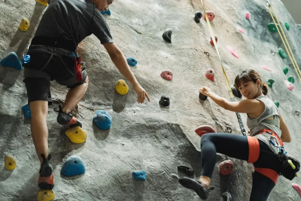Two adults enjoying indoor rock climbing, showcasing strength and camaraderie. Date Night Ideas