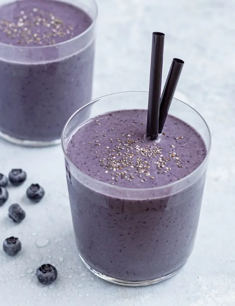 Two glasses of creamy blueberry matcha smoothie sprinkled with chia seeds