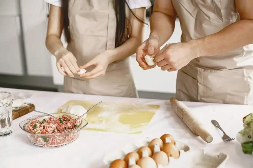 Two people in aprons preparing dough and filling on a kitchen counter. Date Night Ideas